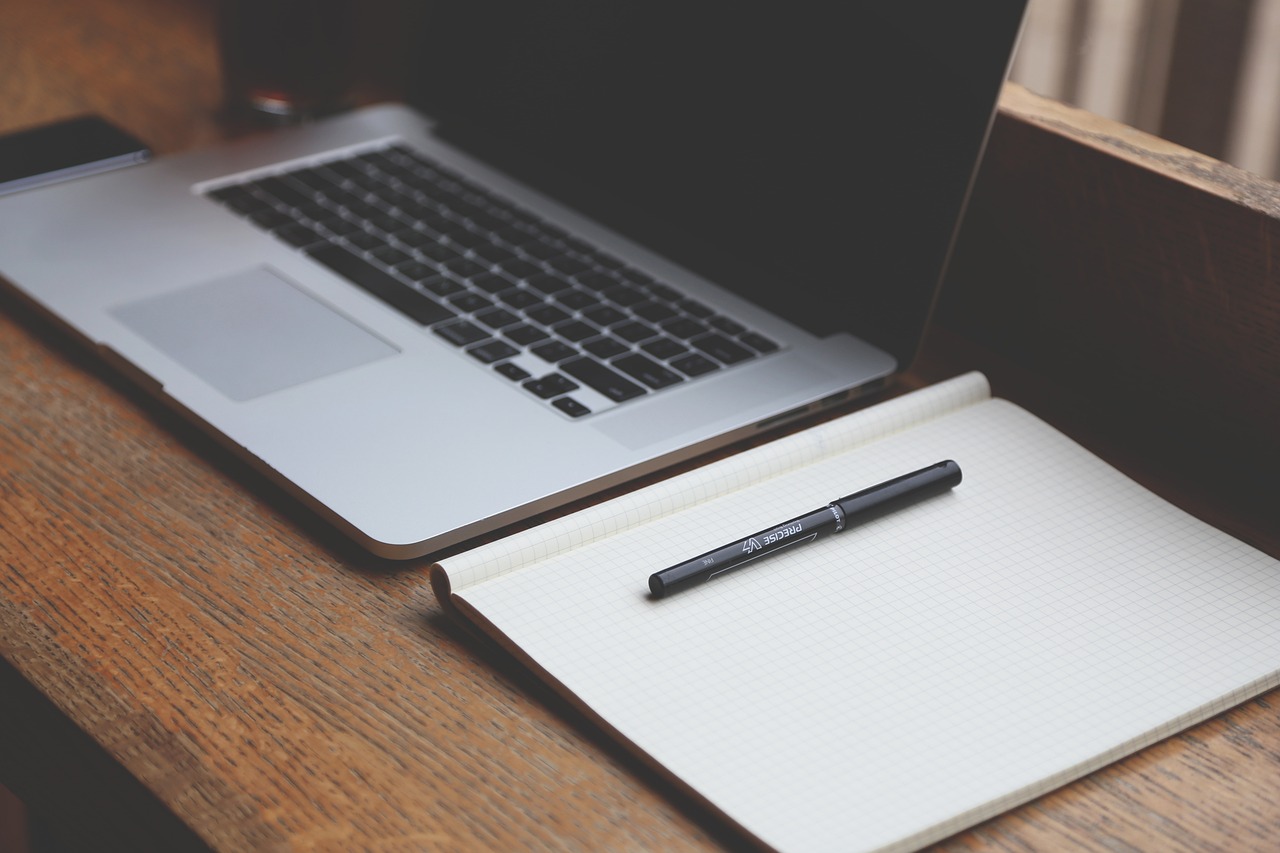 macbook on desk - insurance for sober living research concept